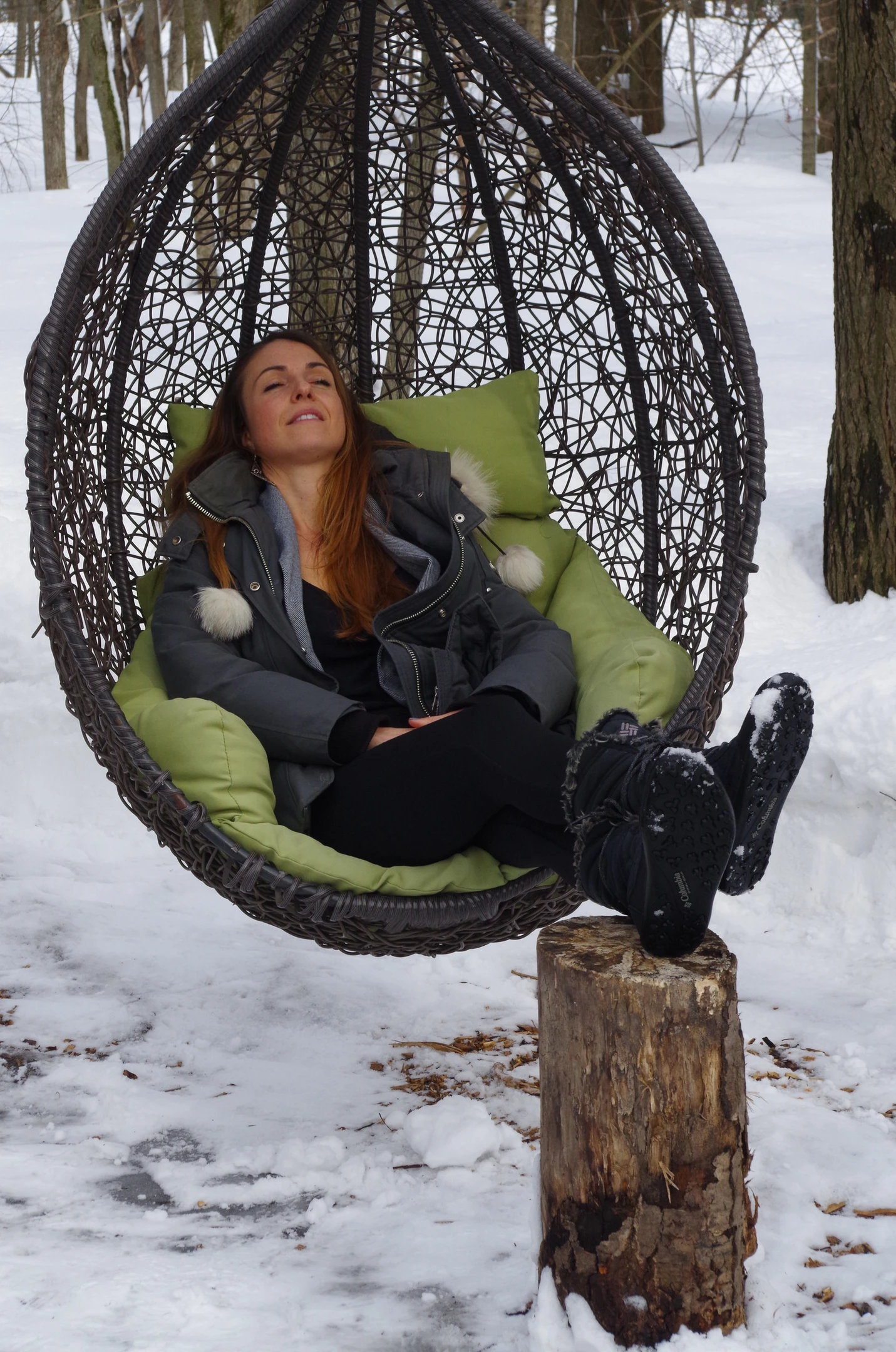 Une femme assise dans un hamac en plein air en hiver dans notre club privé.