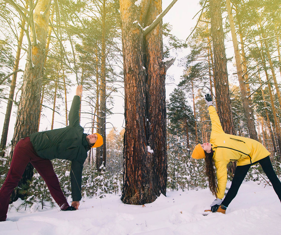 Deux personnes pratiquant le yoga lors d'une activité extérieure en hiver dans notre club privé.